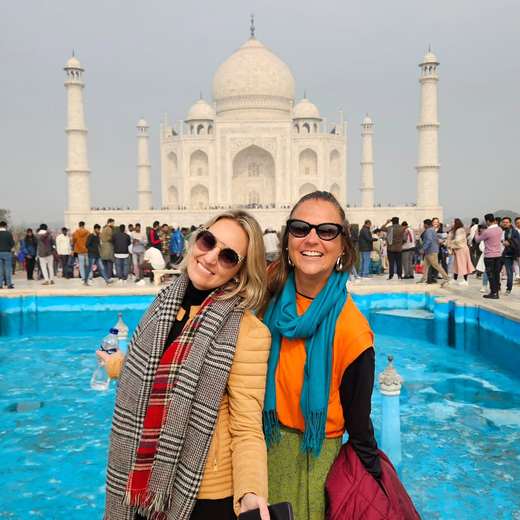 Zwei Freundinnen mit Schals lächeln vor dem Taj Mahal in Indien